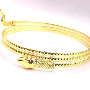 golden coiled snake upper arm cuff bangle, often styled after Egyptian jewelry.